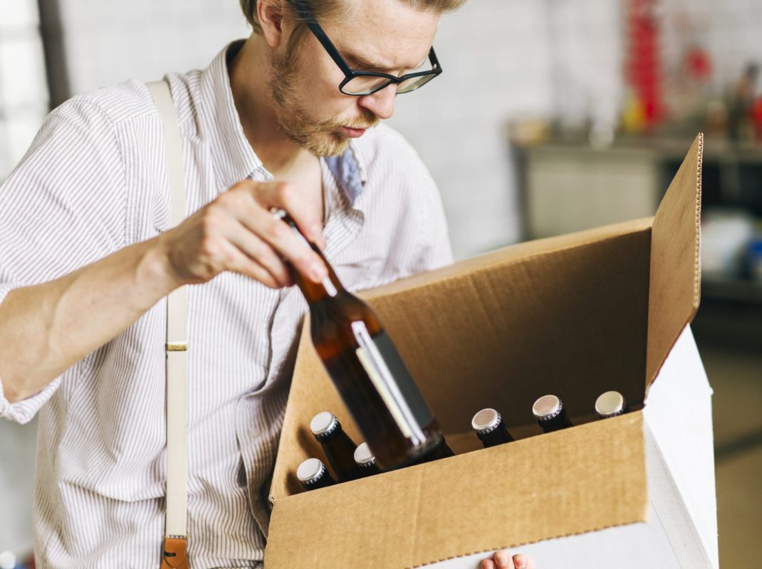 brewery-worker-putting-beer-bottles-into-cardboard-2021-08-28-23-38-31-utc-1-scaled